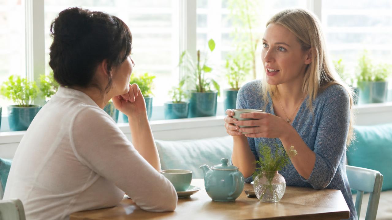 Two people in a bright cafe having a sincere conversation over a cup of tea